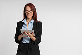 Woman happy smiling cheerful young business executive, worker or student woman with red hair wearing jacket and glasses with tablet tablet computer