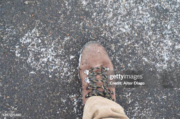 person walking on an icy asphalt surface in winter time. - stamp stockfoto's en -beelden