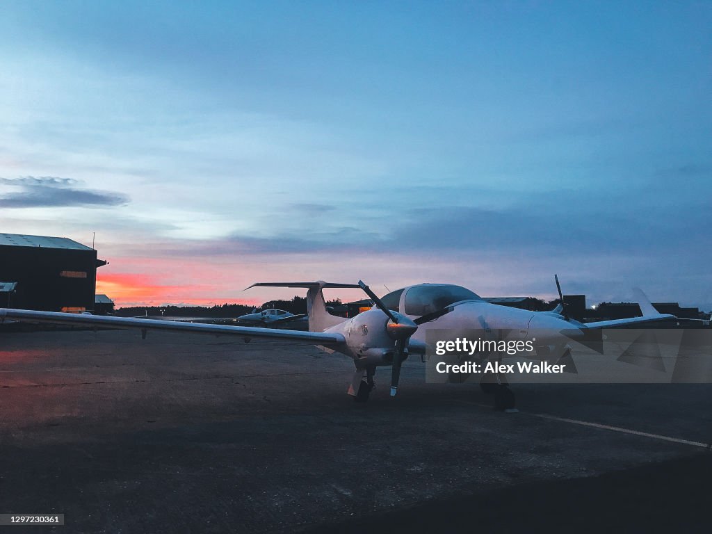 Parked twin engine propeller aircraft at sunrise