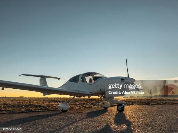 parked small single engine propeller aircraft at sunset - propellervliegtuig stockfoto's en -beelden