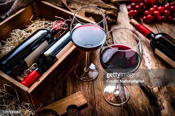 dos copas de vino tinto sobre mesa de madera rústica - winery fotografías e imágenes de stock