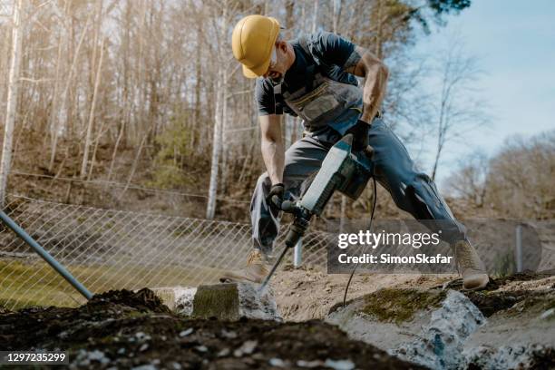 arbeiter bricht beton mit hammer - presslufthammer stock-fotos und bilder