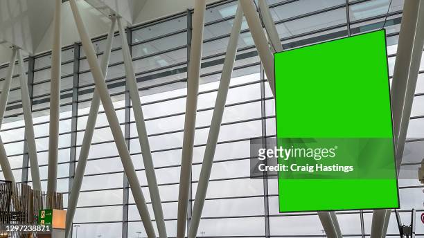 large green screen blank empty marketing billboard sign in airport departure lounge setting. - airport wall stock pictures, royalty-free photos & images