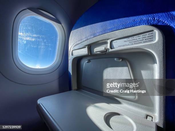 low cost economy airline tray table and window in flight on a sunny day with copy space. - airplane seats stock pictures, royalty-free photos & images