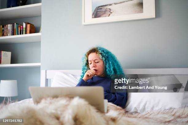 young woman coughing while feeling ill in bed - caucasian woman sick in bed coughing stock pictures, royalty-free photos & images