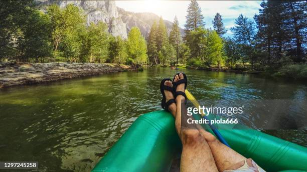 summer vacations in california: pov man cross leg crossed relaxing while rafting in merced river of yosemite - putten stock pictures, royalty-free photos & images