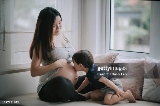asian chinese baby boy kissing his mother's abdomen express love and anticipation for his little sibling new born - belly kissing stock pictures, royalty-free photos & images