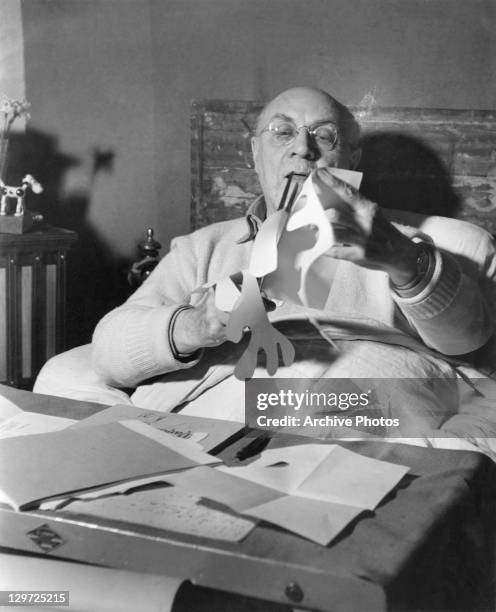 French artist Henri Matisse making paper cutouts in bed at his home in Vence, France, circa 1947.