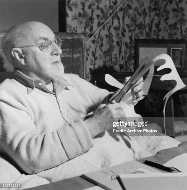 French artist Henri Matisse making paper cutouts in bed at his home in Vence, France, circa 1947.