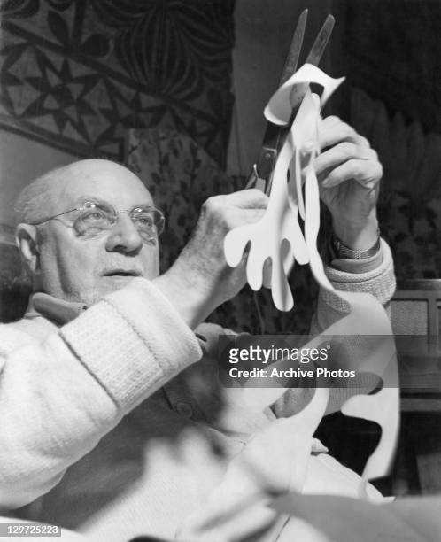 French artist Henri Matisse making paper cutouts in bed at his home in Vence, France, circa 1947.