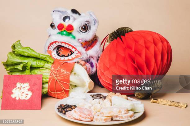 chinese new year traditional ceremony: "采青“ dancing lion trying to eat fresh lettuce wrapped in red paper, meaning "fortune, wealth and good luck" - chinese new year food photos et images de collection