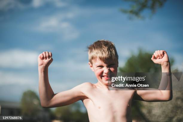 boy showing off his muscles - real people portrait stockfoto's en -beelden