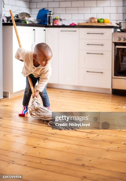 cute little boy trying to mop the kitchen floor at home - kitchen mop stock pictures, royalty-free photos & images