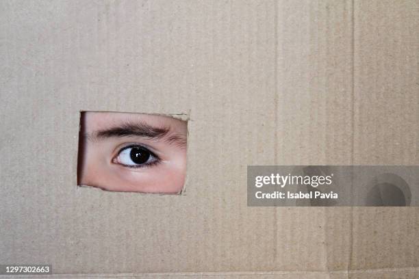 boy looking through a hole on cardboard - looking through an object stock pictures, royalty-free photos & images