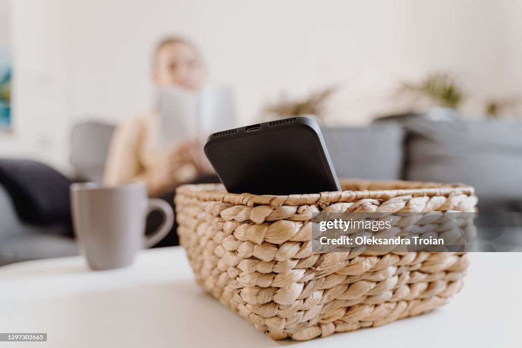 Millennial girl at home refuse using phone and reading a book. Social media addiction. Waste of time. Unplugged. Dependance concept