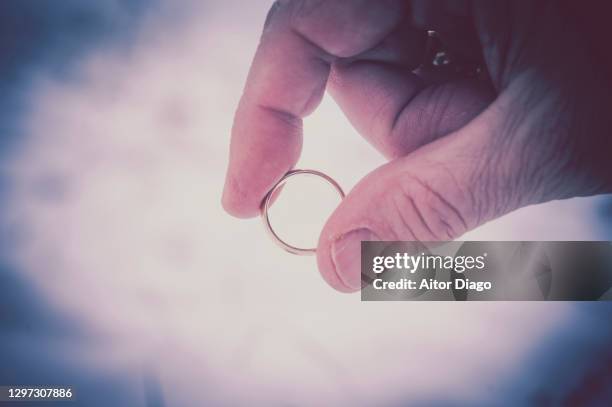 man's hand holds a gold wedding ring in winter time. retro style. - men rings stock pictures, royalty-free photos & images