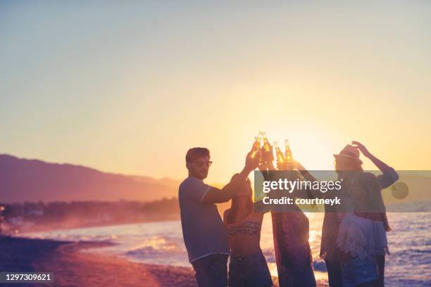 groupe de jeunes fêtant sur la plage au coucher du soleil. - beach music festival photos et images de collection