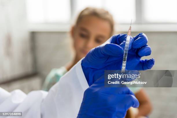 an attractive female doctor gives a vaccine to a child - pharmacy vaccination stock pictures, royalty-free photos & images