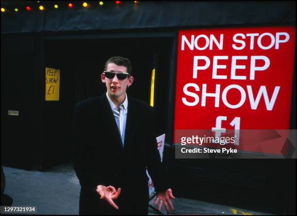 British singer-songwriter and musician Shane MacGowan by the entrance of a 'non-stop peep show' on Old Compton Street in London, England, 1987.