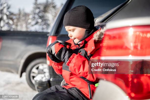 little boy drinking hot chocolate at the car after skiing - après ski stock-fotos und bilder