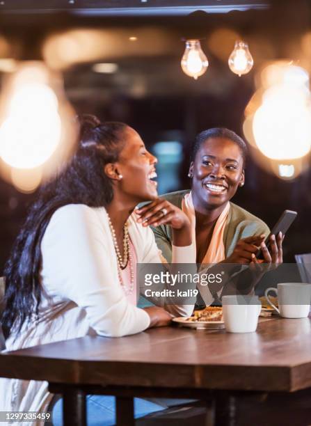 two friends laughing while looking at mobile phone - breakfast close stock pictures, royalty-free photos & images