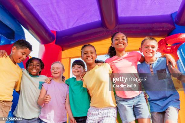 children in bounce house, girl with down syndrome - inflatable playground stock pictures, royalty-free photos & images