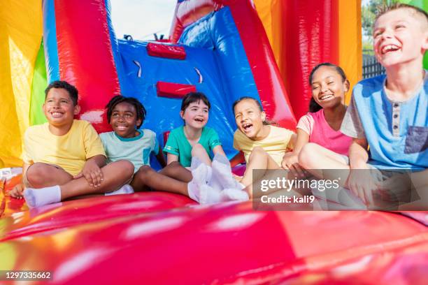 multiethnische kinder in einem hüpfhaus - inflatable playground stock-fotos und bilder