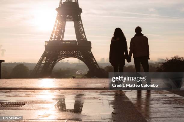 couple embraced near the eiffel tower at sunset, paris - couple paris stock-fotos und bilder