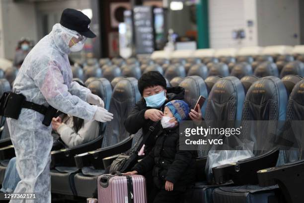 Passenger helps a child put on a mask at Shenyang North Railway Station during the COVID-19 pandemic on January 19, 2021 in Shenyang, Liaoning...