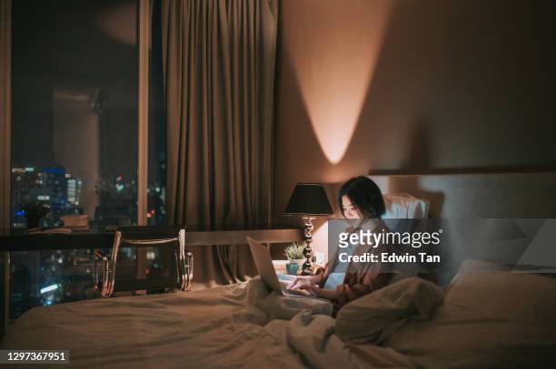 asiatische chinesische schöne frau mit laptop arbeiten von zu hause im schlafzimmer in der nacht - hotel room work stock-fotos und bilder