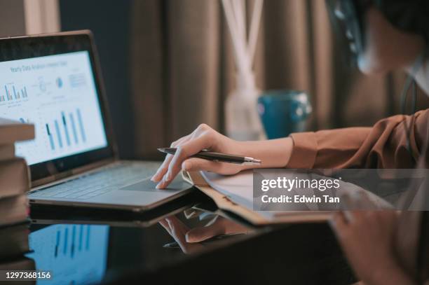 asian chinese beautiful woman using laptop working from home in study room writing headset - business report stock pictures, royalty-free photos & images
