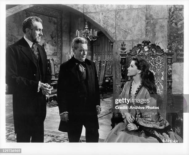 Vincent Price and Frank Maxwell looking at Debra Paget, who's sitting down, in a scene from the film 'Haunted Palace', 1963.