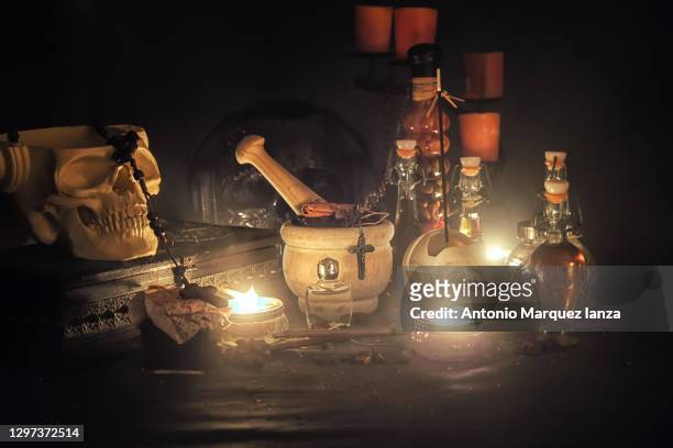 alchemy still life with skull, bottles and book - bruja fotografías e imágenes de stock