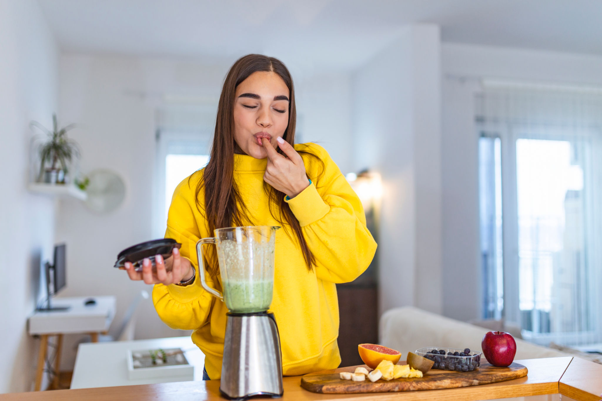 Healthy woman enjoy making green vegetables detox cleanse and green fruit smoothie with blender in kitchen at home. Healthy lifestyle. Beautiful girl tasting smoothie Healthy woman enjoy making green vegetables detox cleanse and green fruit smoothie with blender in kitchen at home. Healthy lifestyle. Beautiful girl tasting smoothie