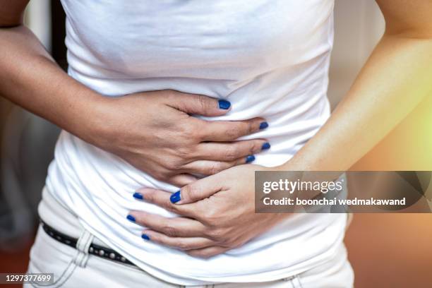 young woman having abdominal pain, upset stomach or menstrual cramps - diarrhoea foto e immagini stock