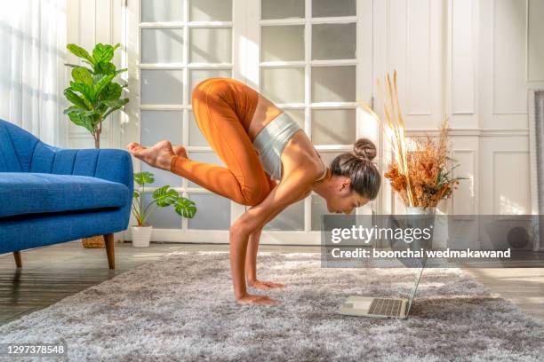 fit woman doing yoga plank and watching online tutorials on laptop, training in living room - computer training stockfoto's en -beelden