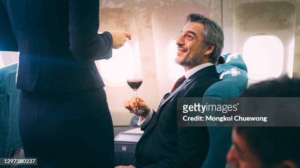 cabin crew serving food to passenger of business class in airplane - upper class stock pictures, royalty-free photos & images
