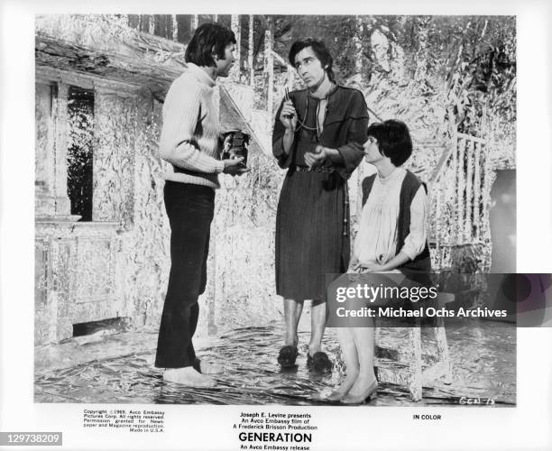 Pete Duel and Sam Waterston stand as Kim Darby sits in a scene from the film 'Generation', 1969.