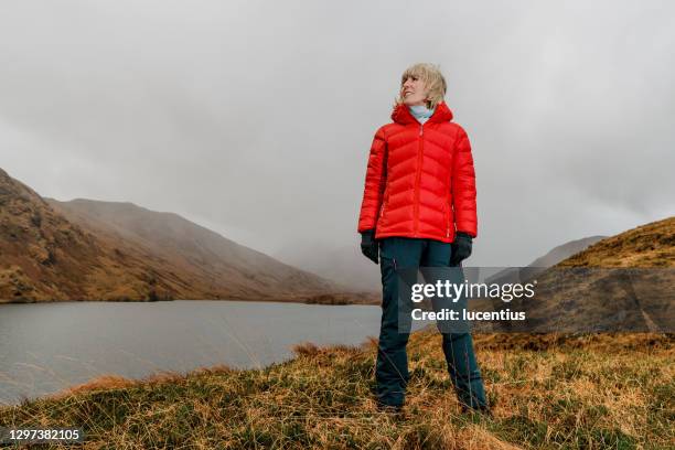 woman in the cold, cloudy, fantastic scottish highlands - red coat stock pictures, royalty-free photos & images