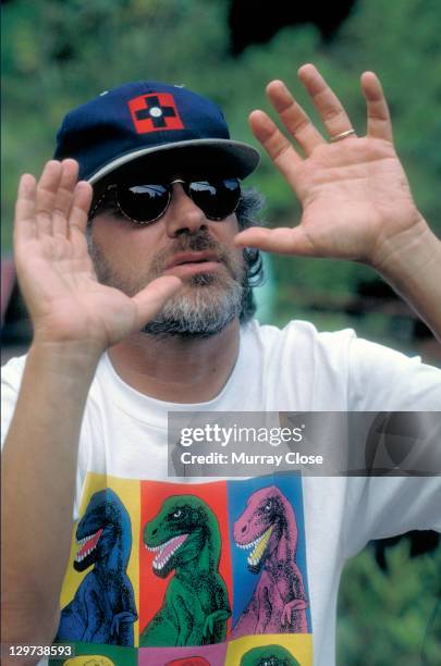 American director Steven Spielberg on the set of the film 'Jurassic Park', 1993. He is wearing a Warhol-inspired dinosaur t-shirt.