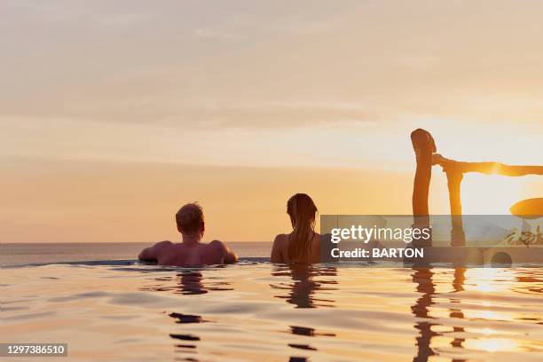 young couple watch ocean sunset from infinity pool - turtle island stock pictures, royalty-free photos & images