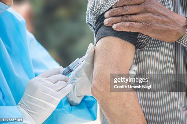 arzthände in chirurgischen handschuhen zur vorbereitung des covid-19-impfstoffs für männliche patienten in indien - village asia stock-fotos und bilder