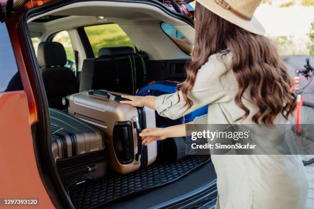 mujer sosteniendo tirando de equipaje en trubk de coche - car trunk fotografías e imágenes de stock