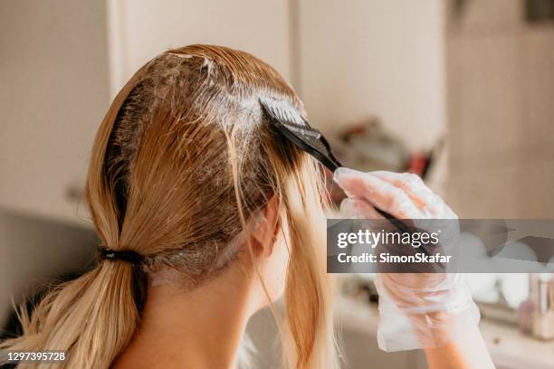 woman dyeing hair in front of mirror - hair coloring stock pictures, royalty-free photos & images