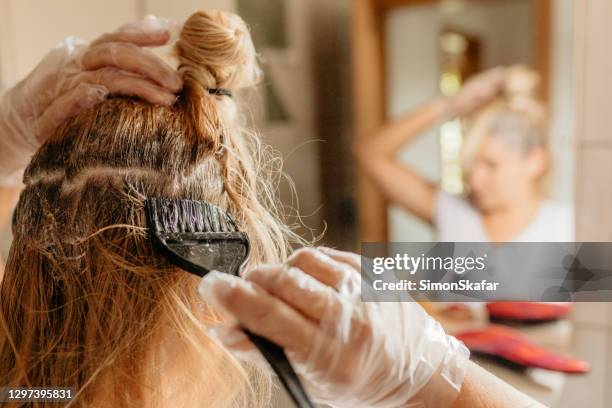 mujer teñindo el pelo frente al espejo - hair dye fotografías e imágenes de stock