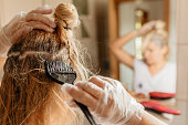 Woman dyeing hair in front of mirror