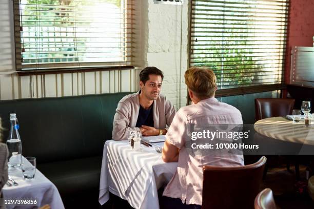 gay couple sitting face to face in restaurant - restaurant atmosphere stock pictures, royalty-free photos & images