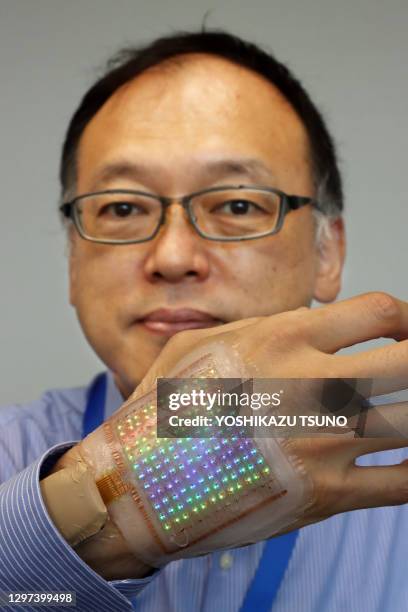 Hiroki Maeda, chercheur japonais de Dai Nippon Printing , présente un prototype d'écran portable à élastique intégral "skin display" pour l'affichage...