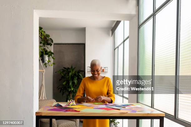 origami artist sitting in studio working with colorful paper - folding origami stock pictures, royalty-free photos & images