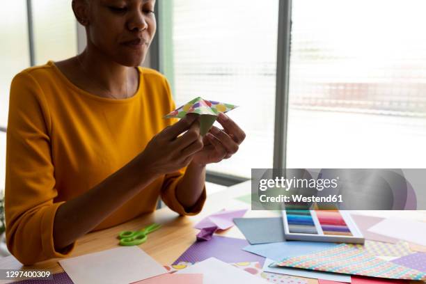 origami artist sitting in studio working with colorful paper - folding origami stock pictures, royalty-free photos & images